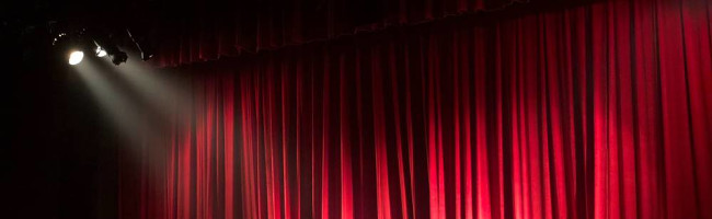 Stage lights shine on a red curtain. 