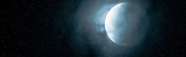 A silver blue moon hovers in the night sky, glowing brightly.