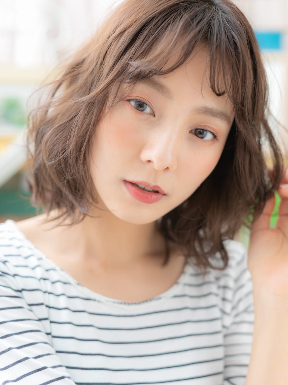 首をかしげるパーマヘアの女性